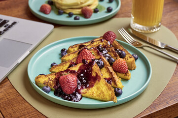 Delicious dish of toasts with jam strawberries and blue berries served with orange juice