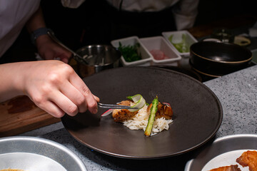 Chef standing at table in kitchen and decorating beautiful dishes in restaurant