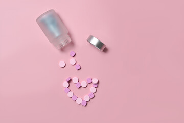 Pills spilling out of a pill bottle on pink background.