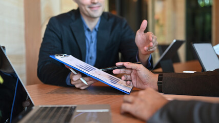 Smiling businessman holding financial documents and explaining information to his colleagues.