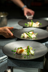 Chefs standing at table in kitchen and decorating beautiful dishes in restaurant
