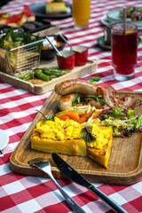 Delicious brunch platter with scramble egg toasts, grilled vegetables, salad, bacon and sausages