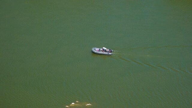 A man floats down the river in a rubber boat with a motor