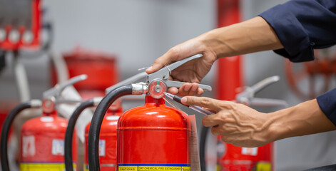 Engineer are checking and inspection a fire extinguishers tank in the fire control room for safety training and fire prevention. - obrazy, fototapety, plakaty