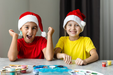 Happy kids making christmas cards wearing santa hats
