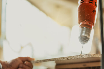 Carpenter drilling a hole in a sheet of chipboard