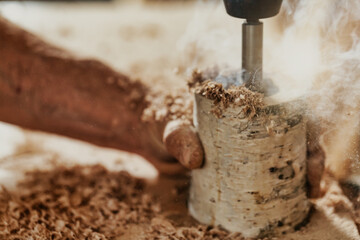 Carpenter drilling into a section of a branch of wood