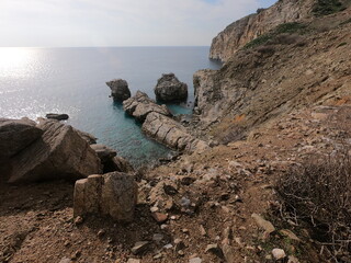 A rocky beach with a rock. Steep cliff to the sea