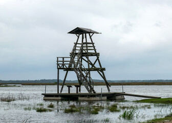 Fototapeta na wymiar view of bird watching tower, cloudy day, gray clouds, landscape with lake and reeds by the lake