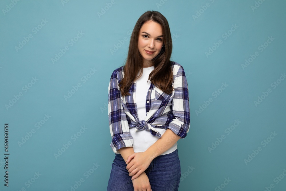 Wall mural Portrait of positive cheerful fashionable woman in hipster outfit isolated on blue background with copy space