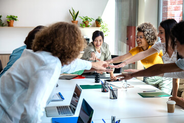 Group of multiracial coworkers join hands to celebrate teamwork success.