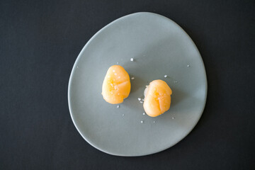 Two Nigiri Sushi with scallop in restaurant served on light-grey plate. Two sushi pieces isolated on black background. Japanese food.
