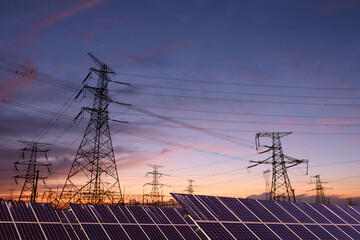 Transmission towers and solar panels are clean energy concepts. Sunset background