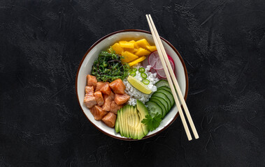 Hawaiian salmon fish poke bowl with rice, mango, radish, cucumber, chukka, sesame seeds, and avocado. Buddha bowl. Diet food. Top view. Flat lay. 