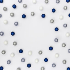 Bright winter holiday frame with sparkling silver and blue balls on white background with copy space.