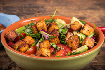 Salad with vegetables, tomatoes, cucumbers, onions, avocado, arugula leaves and fried tofu - modern vegan cuisine