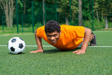 Naklejka premium Spanish footballer warms up and improves his ball control skills by training on the sport ground in the park during the summer.