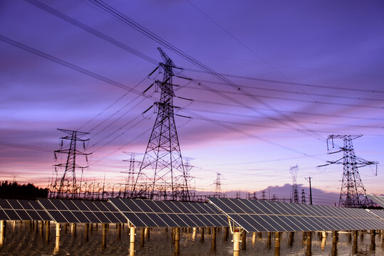 Transmission towers and solar panels are clean energy concepts. Sunset background