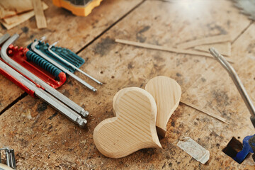 Two decorative wooden heart shapes on a carpentry workbench
