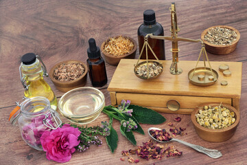 Fototapeta na wymiar Naturopathic skincare healing herbs and flowers to treat eczema, psoriasis and acne with old brass scales for preparation of essential oil treatments. Natural health care concept. On rustic wood.