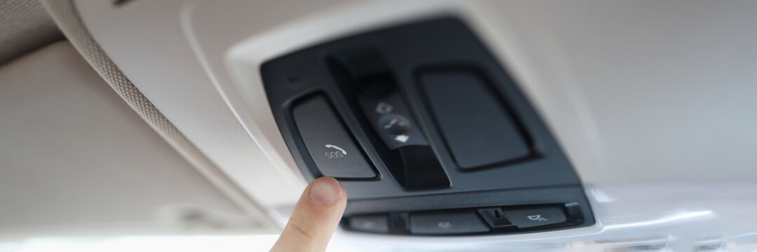 Man with his finger pressing emergency button in car closeup