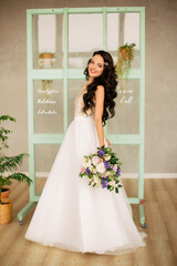 beautiful young girl in a white wedding dress holds a bunch of flowers in her hands. Gorgeous hair