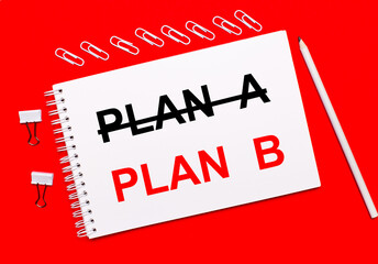 On a bright red background, a white pencil, white paper clips, and a white notebook with the text PLAN B