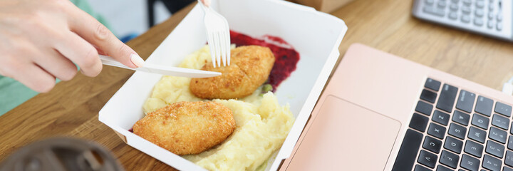 Woman and man eating from cardboard plates with disposable plastic fork and knife in office closeup