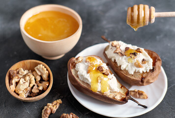 autumn menu dessert, baked pears with ricotta and nuts and honey topping. walnuts and honey in wooden plates on grey table. sweet comforting food for fall season.