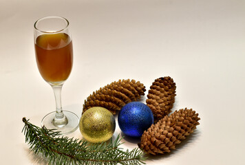 Christmas. Decorations for the Christmas tree glass balls, a glass of wine and Christmas tree cones lie on a white table in the room.