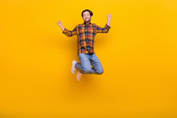 Fototapeta na wymiar Full body photo of funny brunet young guy jump wear shirt jeans sneakers isolated on yellow background