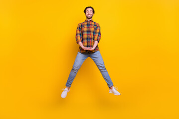 Full body photo of cool brunet young guy jump wear shirt jeans sneakers isolated on yellow background