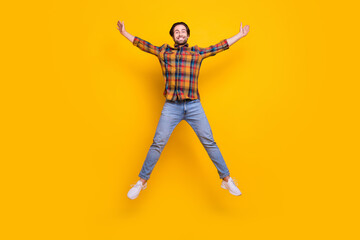 Fototapeta na wymiar Full size photo of sweet brunet millennial guy jump wear shirt jeans sneakers isolated on yellow background