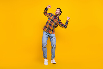 Fototapeta na wymiar Full size photo of funny brunet millennial guy dance look wear shirt jeans sneakers isolated on yellow background