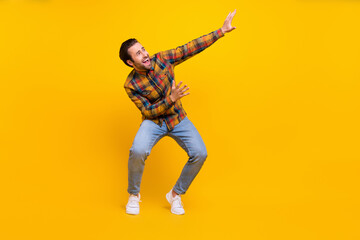 Fototapeta na wymiar Full size photo of crazy brunet young guy dance wear shirt jeans sneakers isolated on yellow background