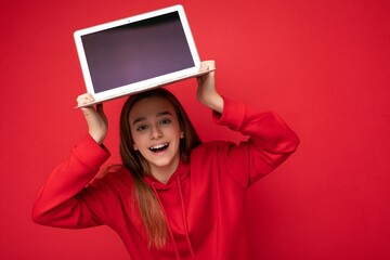 Photo of beautiful young girl holding computer laptop looking at camera isolated over colourful background