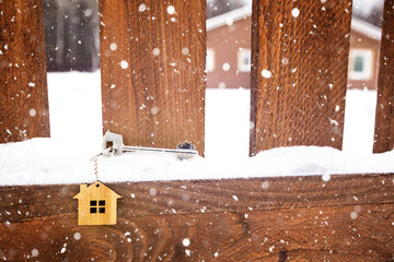 Key to the house on a wooden fence in winter in the snow. A gift for New Year, Christmas. Building, design, project, moving to new house, mortgage, rent and purchase real estate. Copy space