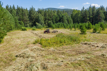 Fototapeta na wymiar Southern Urals. Mountain meadow. Tractor on the hayfield. Aerial view.