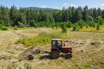 Obraz premium Southern Urals. Mountain meadow. Tractor on the hayfield. Aerial view.