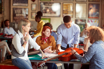 Group of young creative people in the office are enjoying a process of designing a new guitar