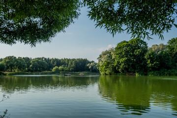 Lake in the park. Green trees, islands, on a pond. People are relaxing and boating. Reflection on the water. Day. Autumn. Russia.