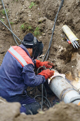 Plumber standing in pit is engaged in elimination of communal accident outdoors. Utility worker...
