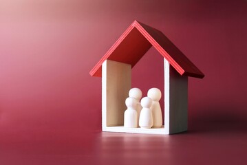 Family care, protection and insurance concept. Wooden dolls family inside a house.