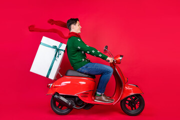 Full length body size photo man smiling on bike wearing scarf delivering gift isolated vivid red color background