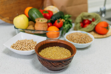 Healthy Breakfast Cereals. Different raw cereals, vegetables, herbs on kitchen table. Fresh raw Breakfast Cereals food on home kitchen. Vegetarian, vegan food cooking ingredients