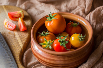 Fresh tomatoes in earthenware. Red, orange and yellow tomatoes on a brown background. Picking tomatoes