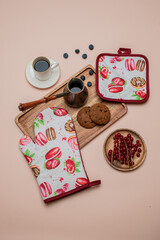 wooden set of potholders, blueberries,
red currant, cup of coffee, biscuits, turk with coffee,  on the light red background 
