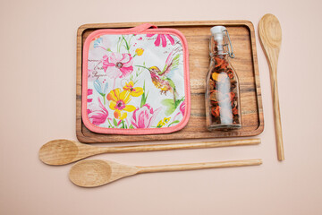 wooden set of potholder bottle of dried flowers wooden spoons on the light red background 