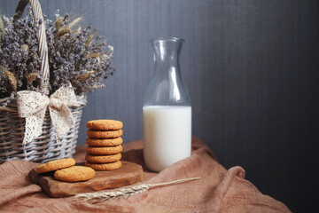 Composition with cookies on a wooden board, milk in a glass bottle and a basket with lavender and spikelets