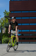 young men in a helmet on a yellow bike - Fxed gear - in the city, on the background of the building